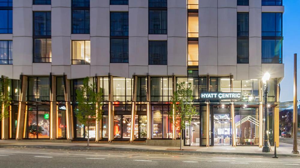 The lit street frontage of the Hyatt Centric Downtown Portland at dusk