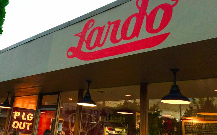 The painted Lardo sign above the restaurant frontage at dusk