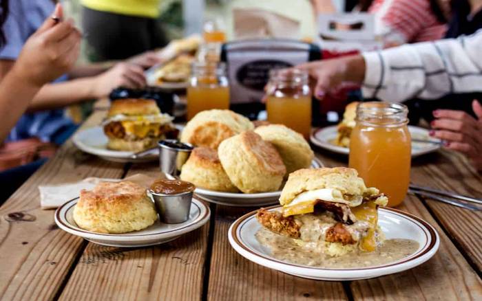 Biscuit sandwiches and jars of juice on a picnic table at Pine State Biscuits