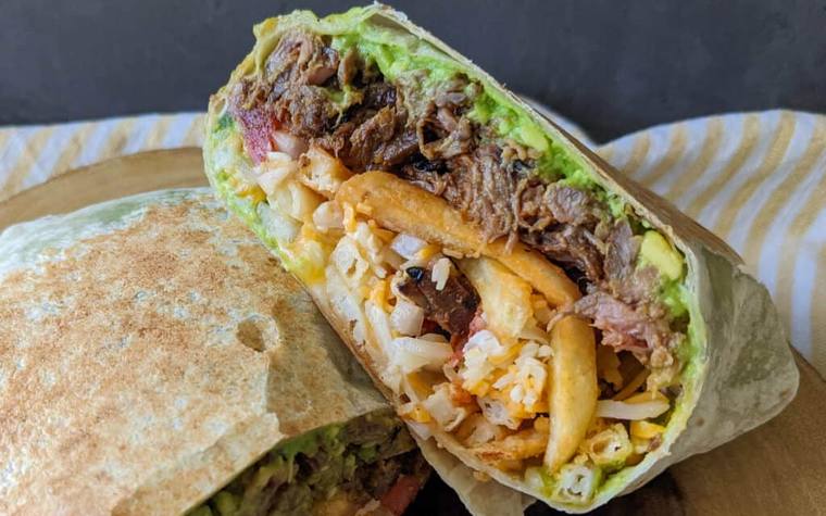 A California burrito cut open, showing carne asada, cheese, guacamole and french fries