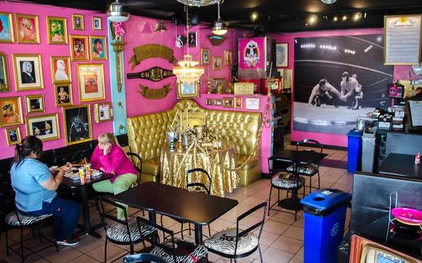 The pink and gold luchador-themed dining room at Lucha Libre Taco Shop