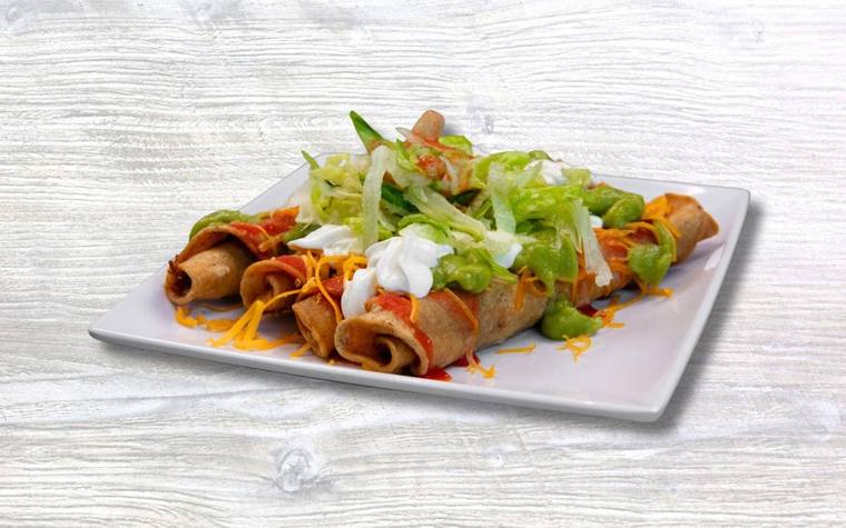 A plate of rolled tacos topped with cheese, guacamole and lettuce